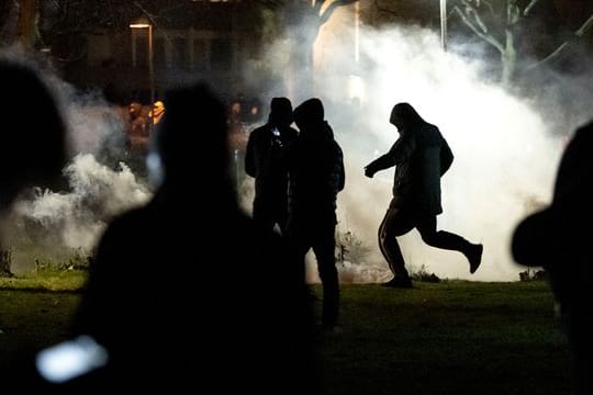 Menschen werden von Rauch umhüllt, nachdem im Stadtteil Rosengard in Malmö Proteste ausgebrochen sind.