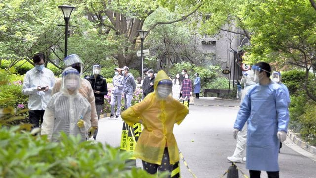 Bewohner einer Wohnanlage in Shanghai warten auf die Durchführung von PCR-Tests.