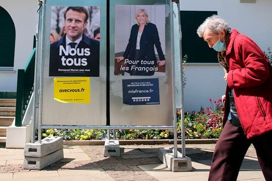 Eine Frau geht im Südwesten Frankreichs an Wahlkampfplakaten der französischen Präsidentschaftskandidaten Macron und Le Pen vorbei.