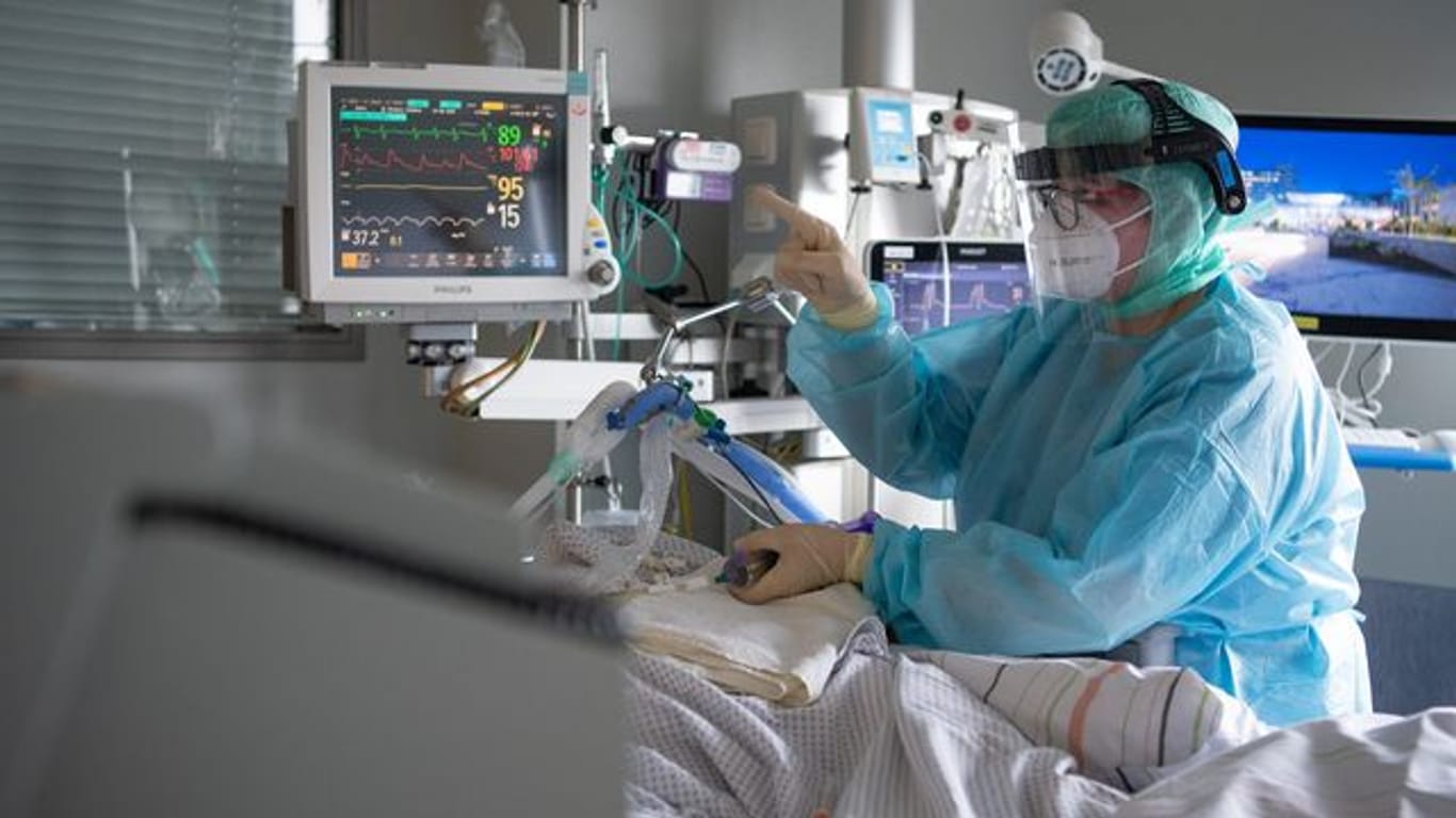 Eine Intensiv-Pflegerin versorgt einen schwer an Corona erkrankten Patienten auf der Intensivstation des Klinikums in Fulda.