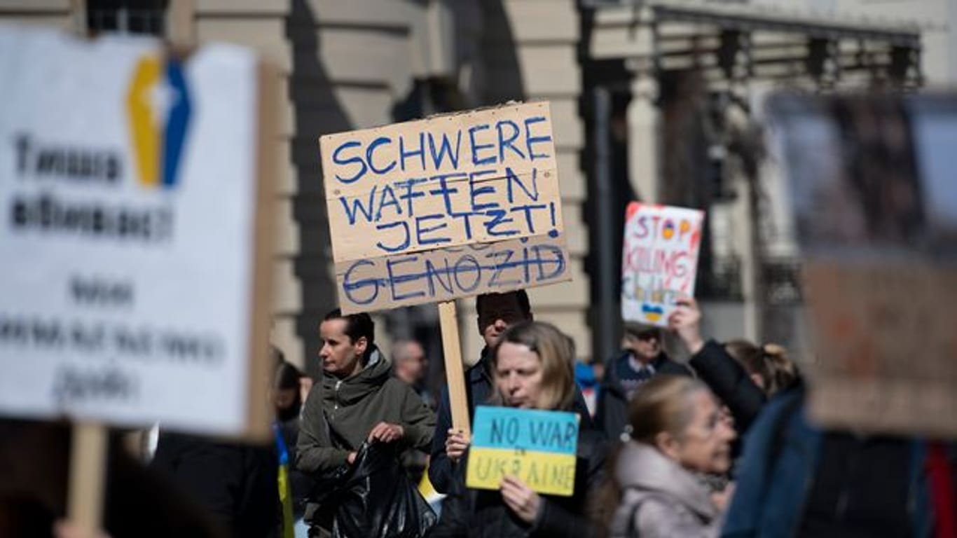 "Schwere Waffen jetzt" steht auf einem Plakat bei einer Demonstration gegen den Krieg in der Ukraine in Berlin.