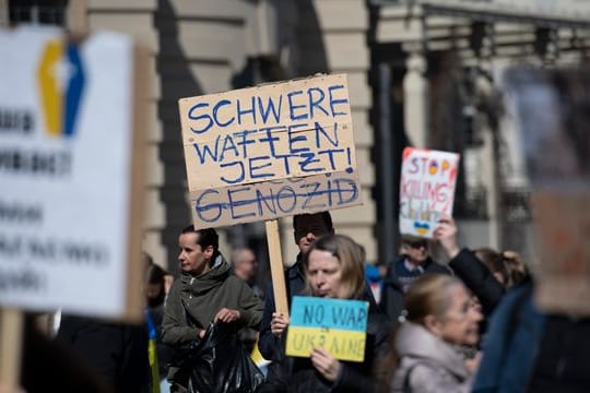 "Schwere Waffen jetzt" steht auf einem Plakat bei einer Demonstration gegen den Krieg in der Ukraine in Berlin.