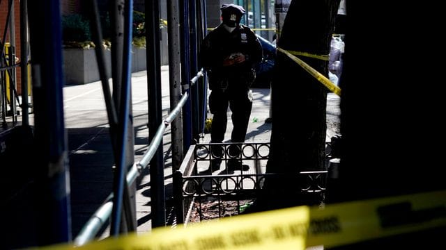 Ein Polizeibeamter steht in der Nähe des Tatorts, an dem eine junge Frau bei einer Schießerei in einem Wohnhaus in Brooklyn getötet wurde. Ein Polizeibeamter steht in der Nähe des Tatorts, an dem eine junge Frau bei einer Schießerei in einem Wohnhaus in Brooklyn getötet wurde.