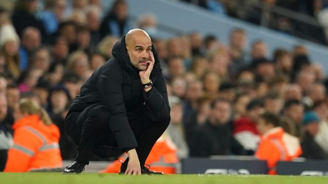 Pep Guardiola, Trainer von Manchester City, hockt an der Seitenlinie und studiert das Spiel seiner Mannschaft.