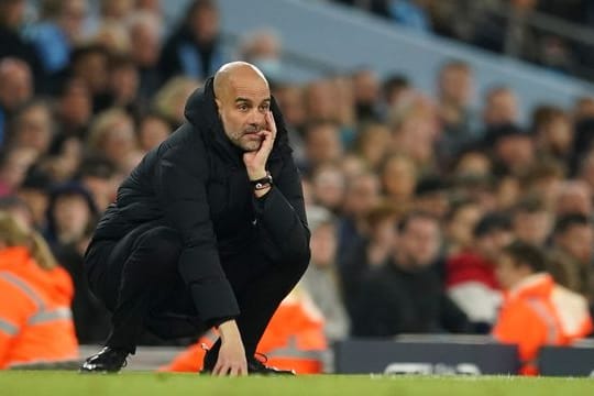 Pep Guardiola, Trainer von Manchester City, hockt an der Seitenlinie und studiert das Spiel seiner Mannschaft.