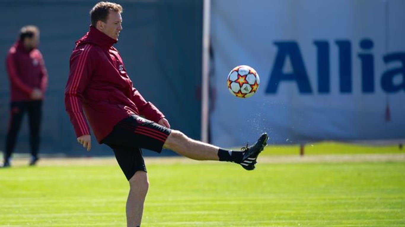 Bayern-Trainer Julian Nagelsmann hält während des Trainigs einen Ball hoch.