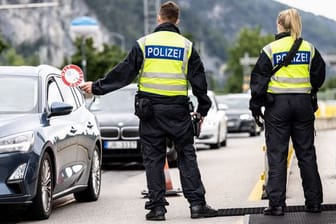 Deutsche Bundespolizisten beobachten an der Grenze zu Österreich auf der Autobahn A93 den Verkehr.