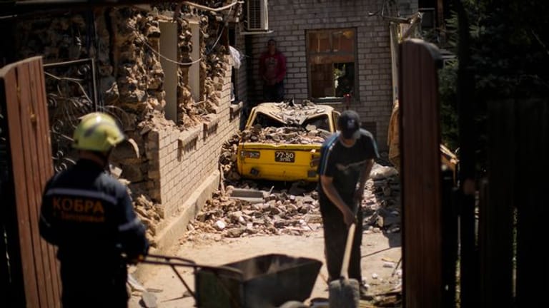 Rettungskräfte und Anwohner von Saporischschja entfernen Trümmer zerstörter Häuser.