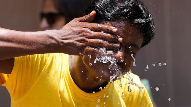 Ein Mann spritzt sich an einem extrem heißen Tag auf einem Marktplatz in Mumbai Wasser ins Gesicht. Ein Mann spritzt sich an einem extrem heißen Tag auf einem Marktplatz in Mumbai Wasser ins Gesicht.