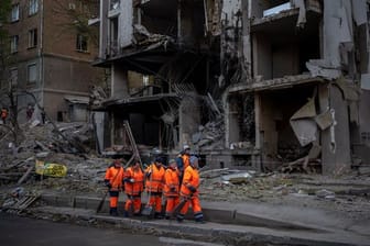 Ein Aufräumtrupp vor einem durch Raketenbeschuss zerstörten Gebäude in Kiew.
