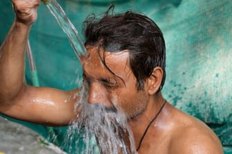 Ein Mann kühlt sich in Lucknow (Uttar Pradesh) in einer öffentlichen Wasserstelle ab.