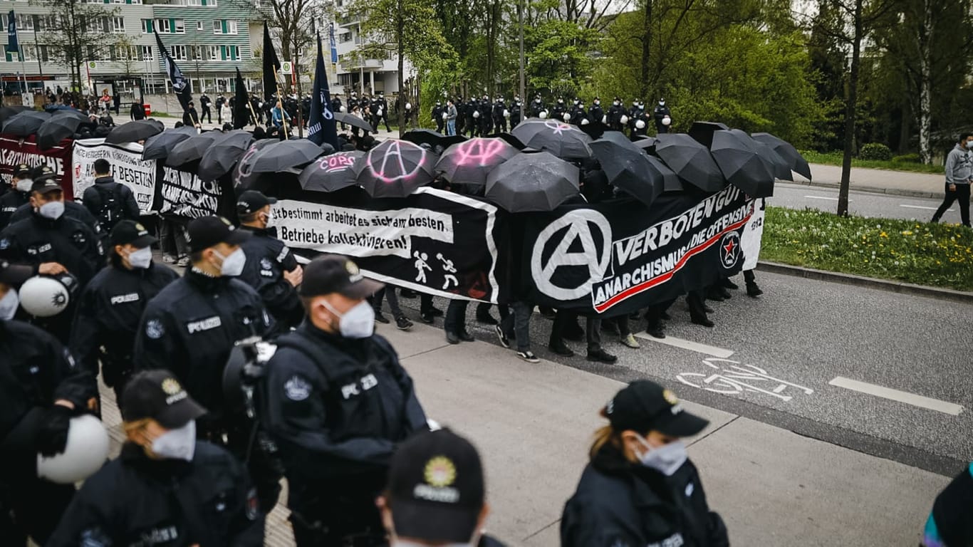 Anarchisten verdecken sich mit Transparenten und Regenschirmen vor der Polizei: Der Protestzug lief am Abend durch Wilhelmsburg.