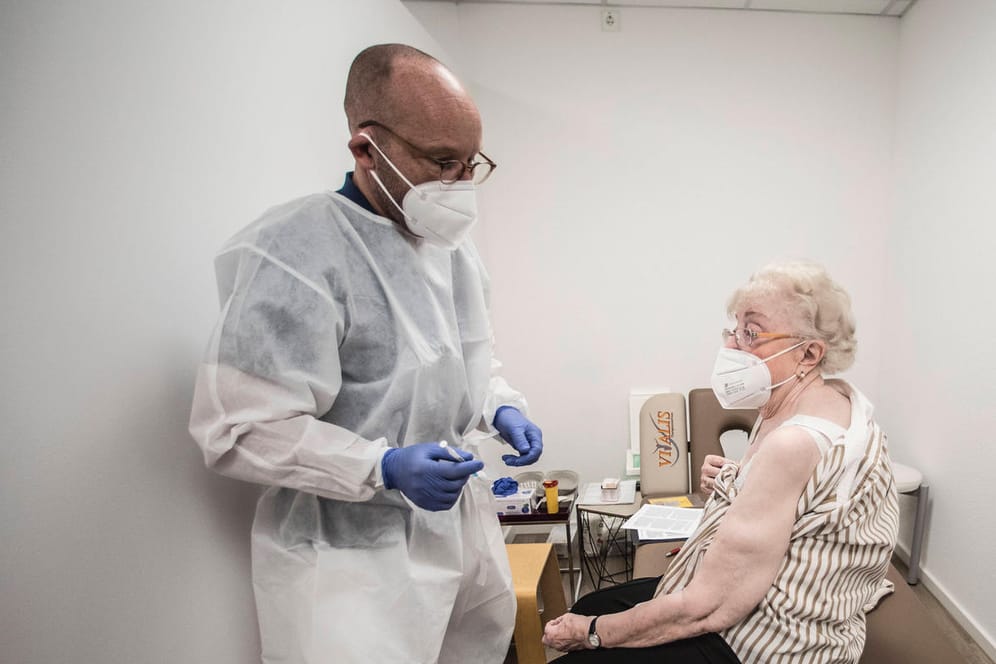 Ein Arzt impft eine ältere Frau (Symbolbild): in Deutschland geht die Inzidenz zurück, es gibt aber noch eine Impflücke bei Boostern.