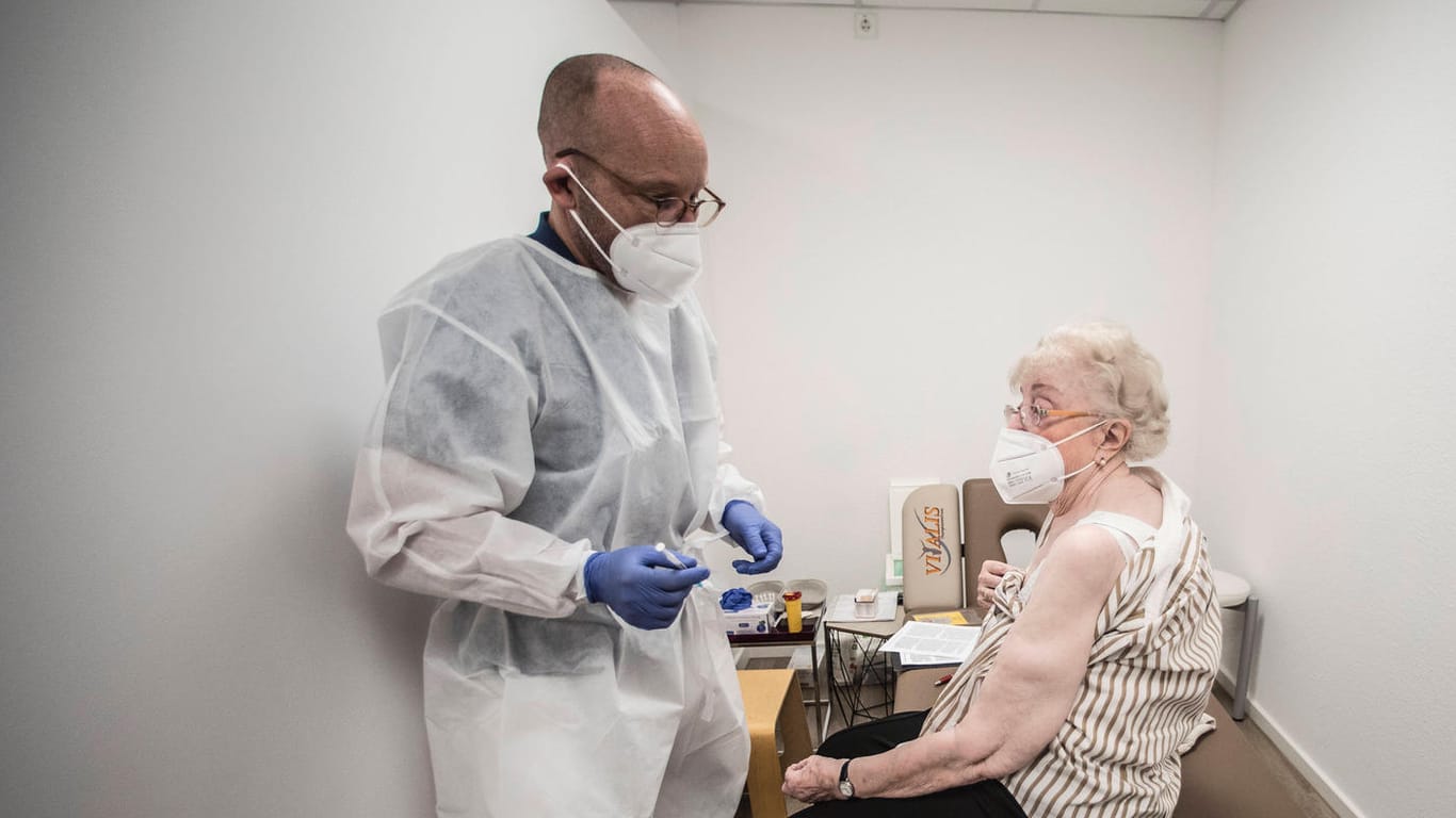 Ein Arzt impft eine ältere Frau (Symbolbild): in Deutschland geht die Inzidenz zurück, es gibt aber noch eine Impflücke bei Boostern.