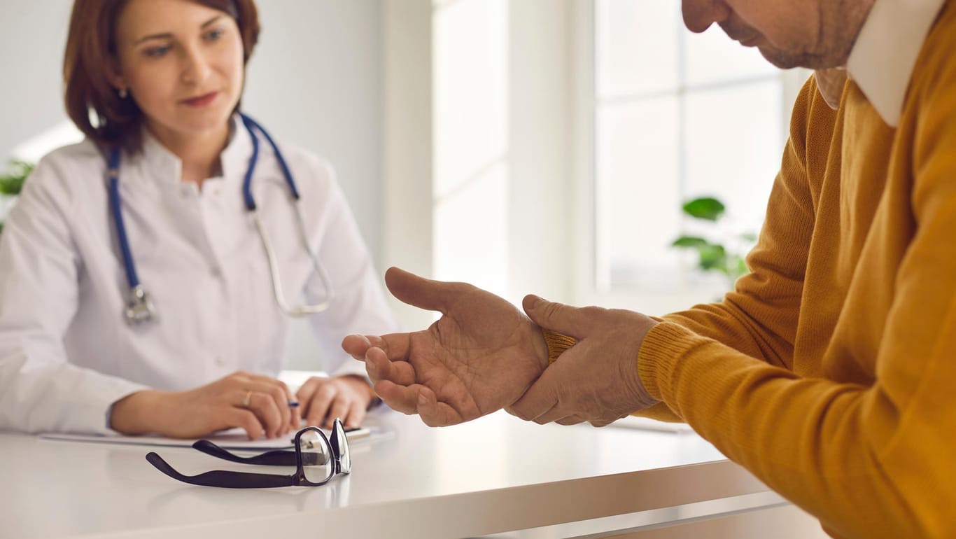 Patient erläutert Ärztin seine Symptome (Hand): Rheuma macht sich zu Beginn häufig in den Fingern bemerkbar und sollte bei Verdacht möglichst schnell behandelt werden.