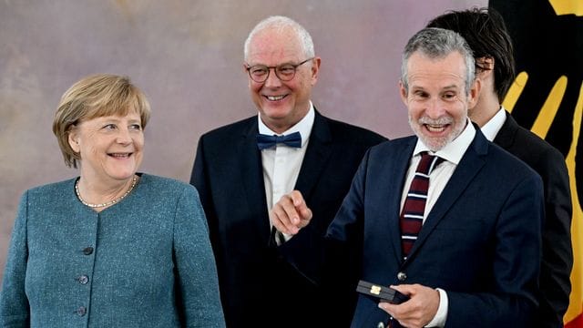 Angela Merkel (l-r), Autor Jean-Claude Kuner und der Verdienstkreuzträger Ulrich Matthes im Schloss Bellevue.