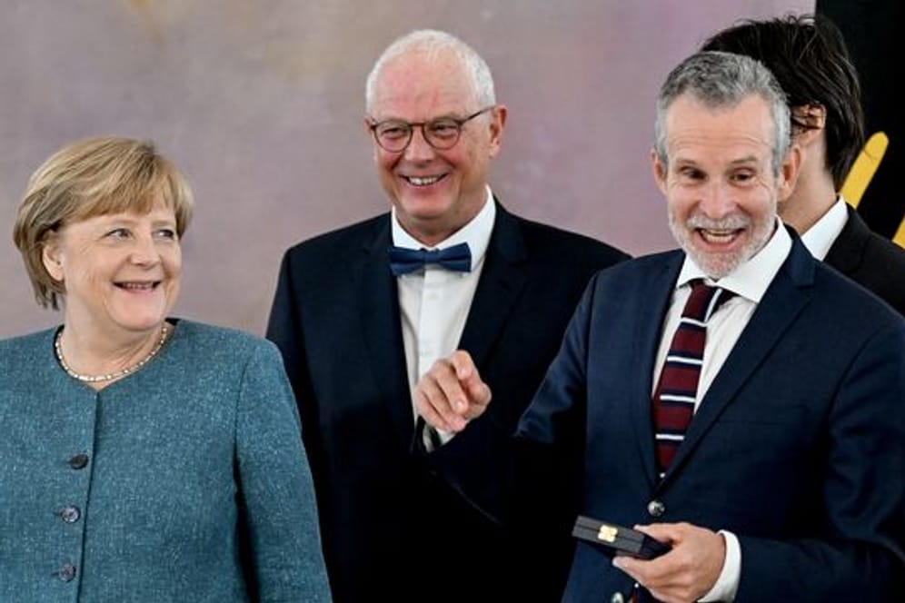 Angela Merkel (l-r), Autor Jean-Claude Kuner und der Verdienstkreuzträger Ulrich Matthes im Schloss Bellevue.
