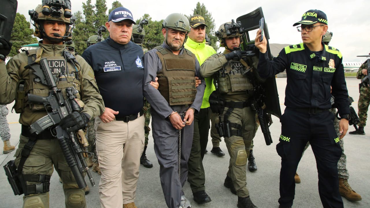 Die Polizei eskortiert Dairo Antonio Usuga (Mitte) auch bekannt als "Otoniel" auf einem Militärflughafen in Bogota: Der Drogenboss wurde an die USA ausgeliefert. Die Polizei eskortiert Dairo Antonio Usuga (Mitte) auch bekannt als "Otoniel" auf einem Militärflughafen in Bogota: Der Drogenboss wurde an die USA ausgeliefert.