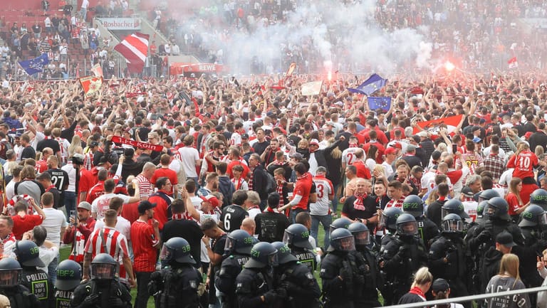 Überwältigt: Die Kölner Fans feiern den Europa Cup auf dem Rasen im Stadion.