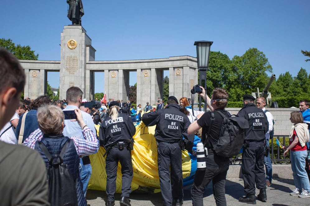 Polizisten rollen eine ukrainische Flagge ein(Archivbild): Bei den russischen Gedenkveranstaltungen in Berlin sind russische und ukrainische Fahnen verboten.