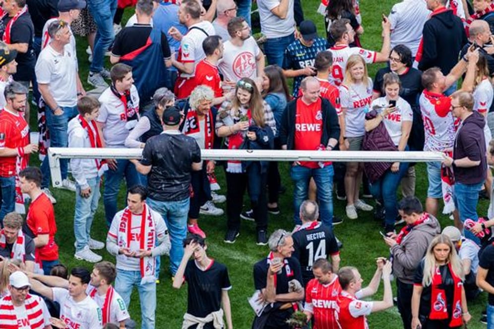 Kölner Fans halten nach einem Platzsturm einen Torpfosten.