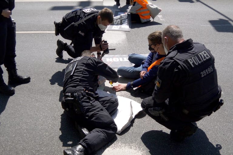 Polizisten beim Ablösen der Aktivisten: Drei Aktivisten blieben auf der Straße.