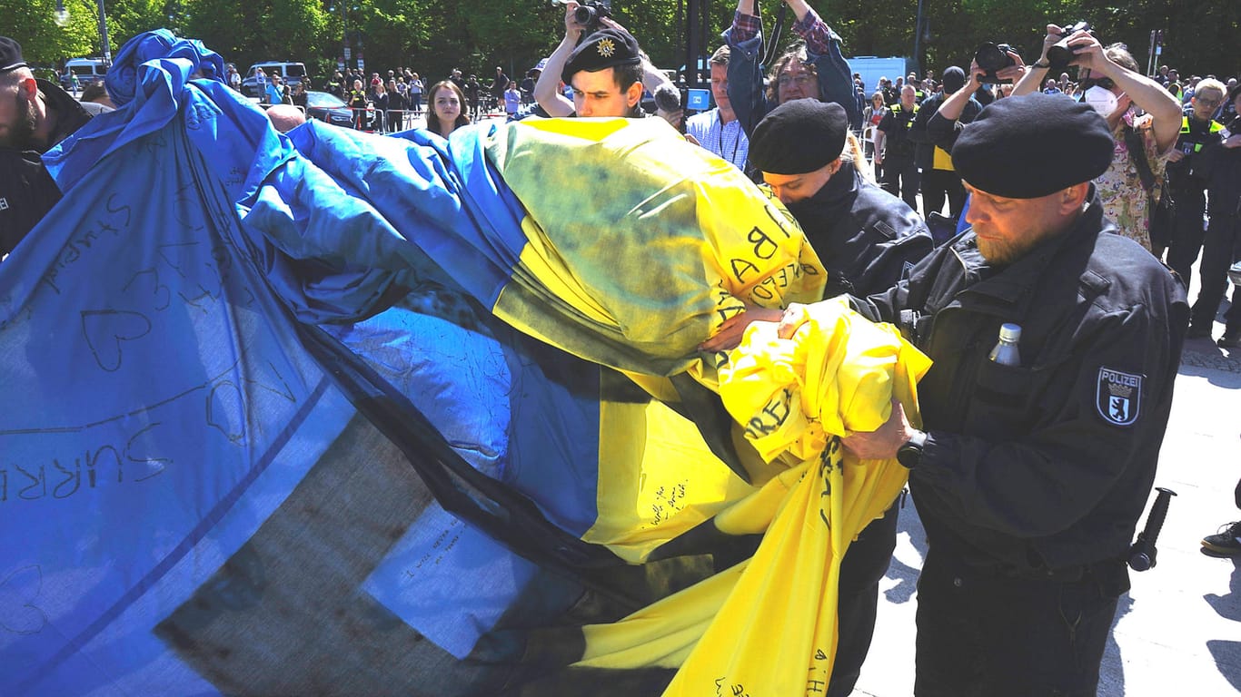 Polizisten rollen eine ukrainische Fahne ein: Die Bilder sorgten etwa beim ukrainischen Botschafter Melnyk für Empörung.