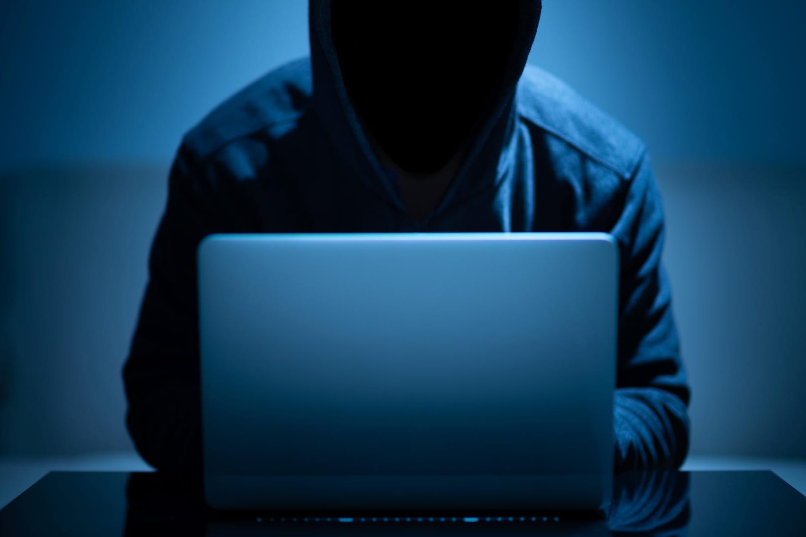 Hacker dark face using laptop