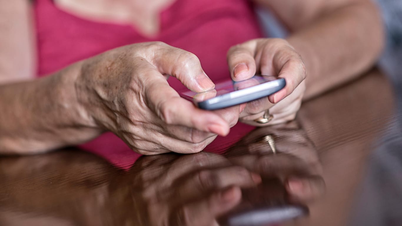 Ältere Frau am Smartphone.Intensives Tippen und Wischen auf dem Handy reizt die Sehnen und belastet die Gelenke.
