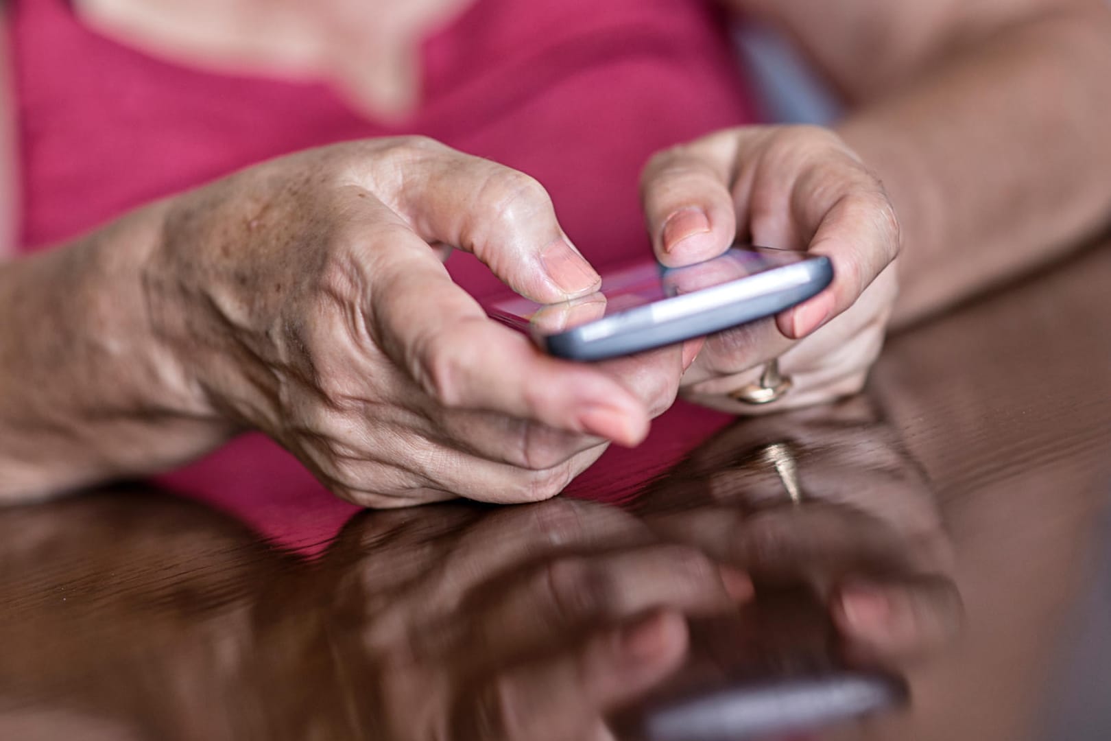 Ältere Frau am Smartphone.Intensives Tippen und Wischen auf dem Handy reizt die Sehnen und belastet die Gelenke.