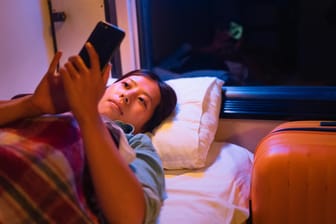 Eine Frau liegt in der Kabine eines Nachtzuges: Durch Nachtzüge kann man im Schlaf sein Ziel erreichen.