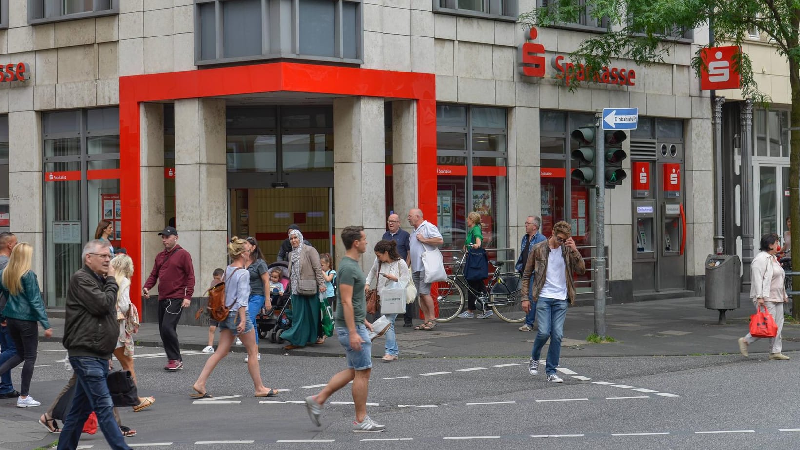 Menschen vor einer Sparkasse (Archivbild): Viele Geldhäuser in Deutschland setzen auf Strafzinsen für ihre Kunden.