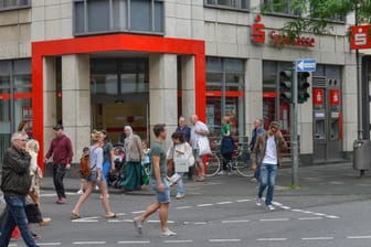 Menschen vor einer Sparkasse (Archivbild): Viele Geldhäuser in Deutschland setzen auf Strafzinsen für ihre Kunden.