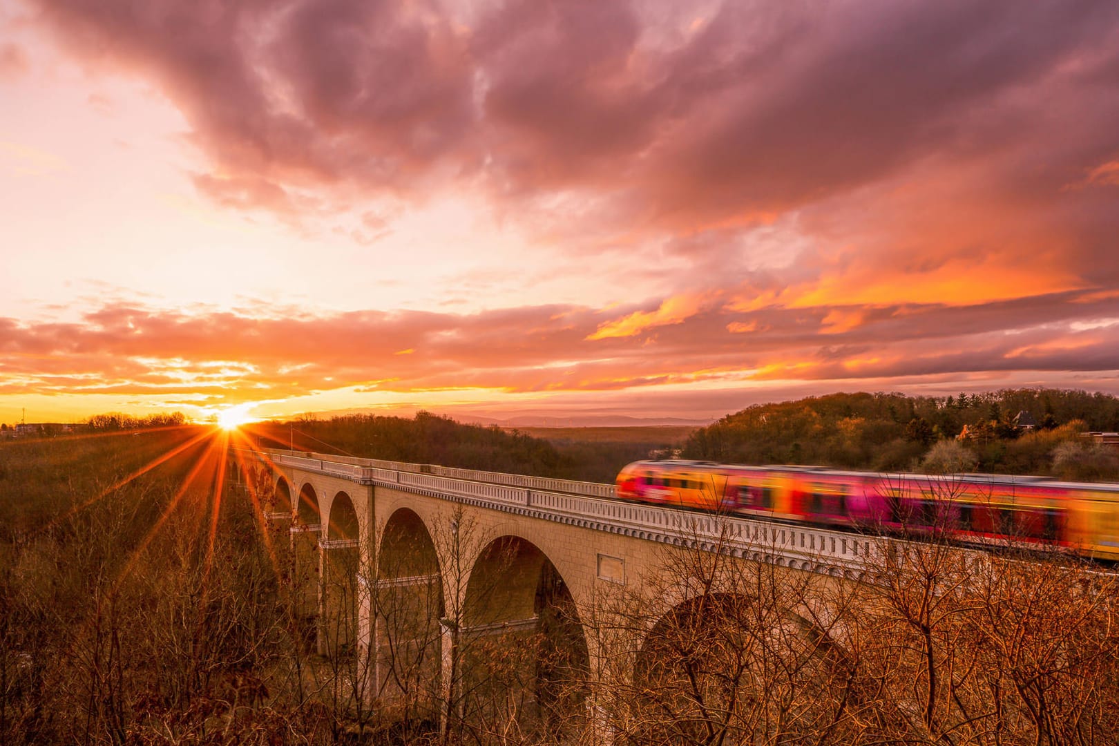 Eine Regionalbahn fährt in den Sonnenaufgang nahe der sächsischen Stadt Görlitz: Mit dem 9-Euro-Ticket können viele schöne Ausflugsziele erreicht werden.