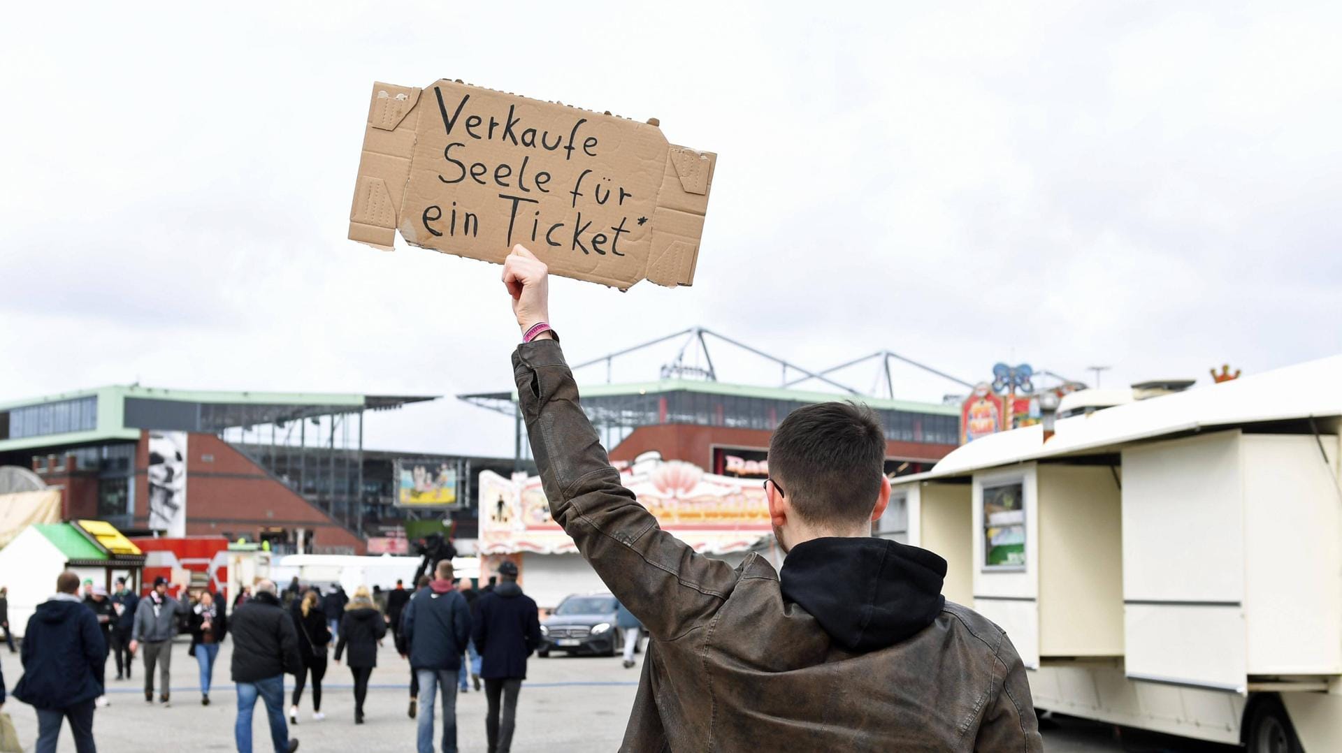 Ein Mann hält ein Schild hoch, auf dem er nach einem Ticket für ein Fußballspiel sucht (Archivbild). Ein Mann hält ein Schild hoch, auf dem er nach einem Ticket für ein Fußballspiel sucht (Archivbild).