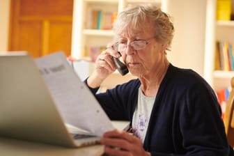 Ältere Frau checkt Unterlagen (Symbolbild): Wie viele Rentner rutschen wegen der Rentenerhöhung erstmals in die Steuerpflicht?