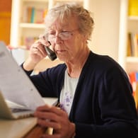 Ältere Frau checkt Unterlagen (Symbolbild): Wie viele Rentner rutschen wegen der Rentenerhöhung erstmals in die Steuerpflicht?