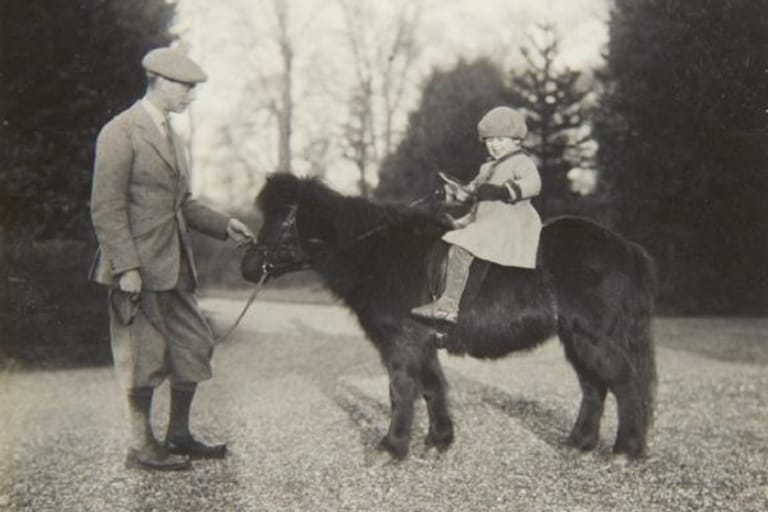 Mai 1930: Die Queen als junges Mädchen auf einem Shetlandpony, neben ihr steht ihr Vater.