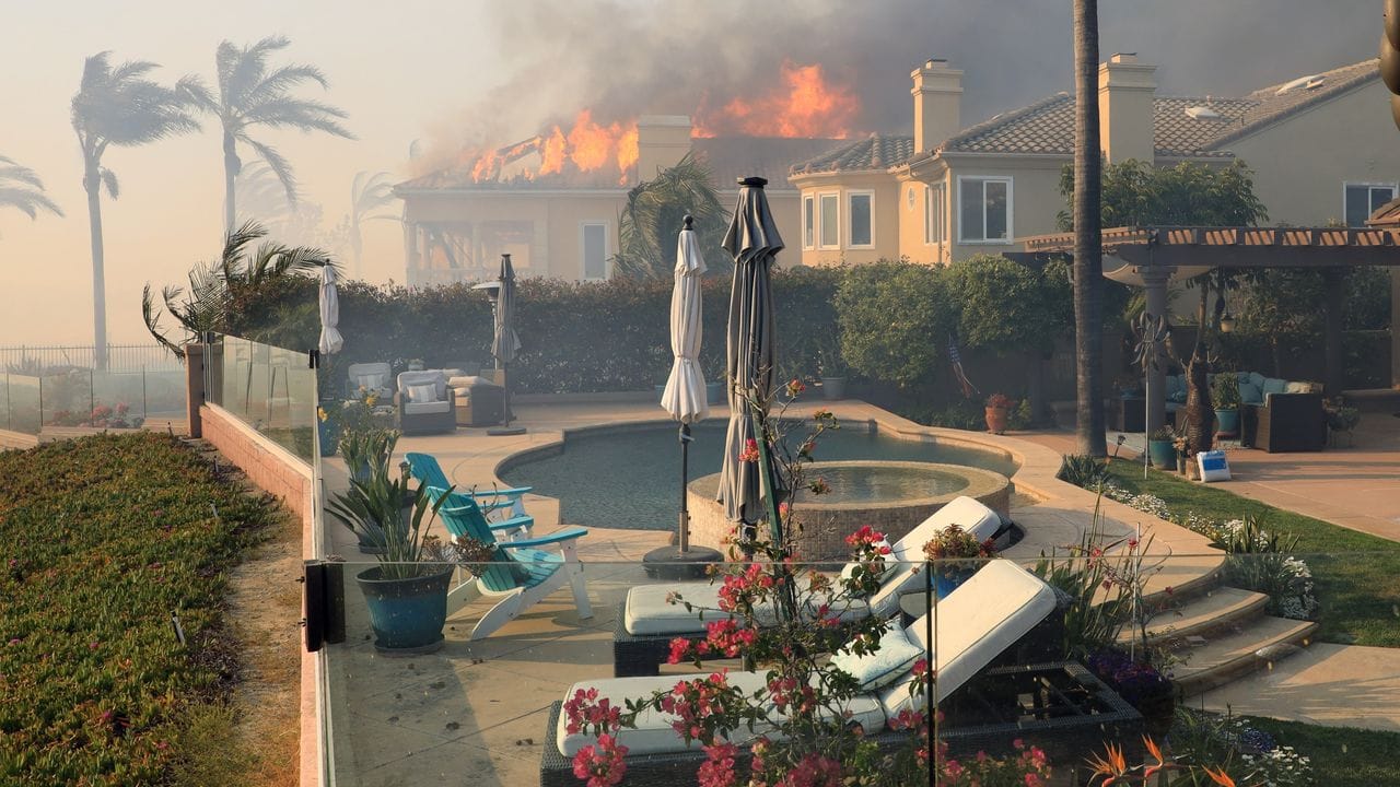 Flammen eines windgetriebenen Lauffeuers zerstören ein Gebäude in Südkalifornien.