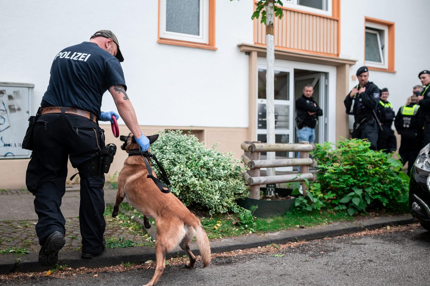 Ein Polizist mit Spürhund vor Wohnhaus des Tatverdächtigen: Bei dem 16-Jährigen wurden mehrere Waffen gefunden.