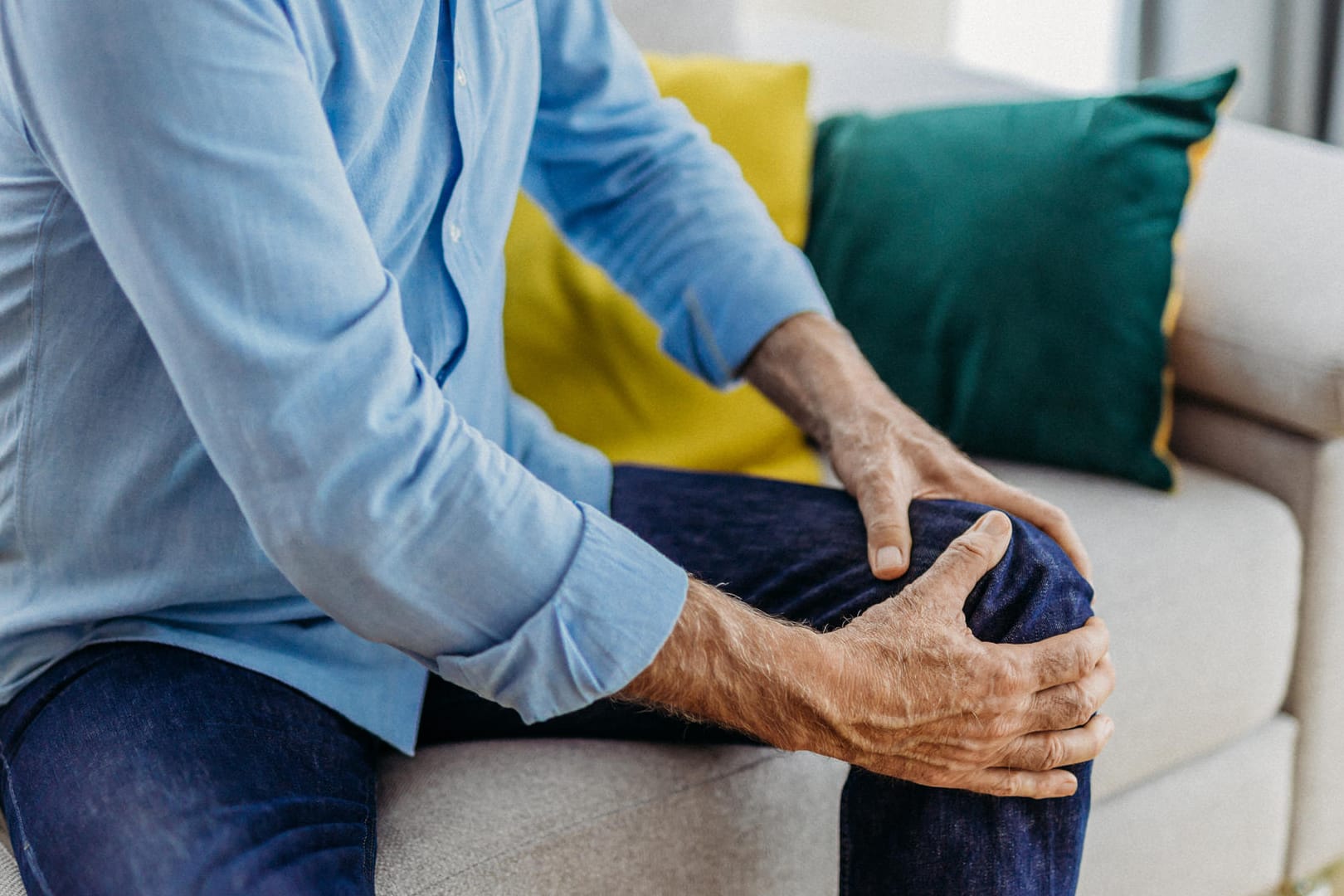 Ein sitzender Mann greift sich ans schmerzende Knie.