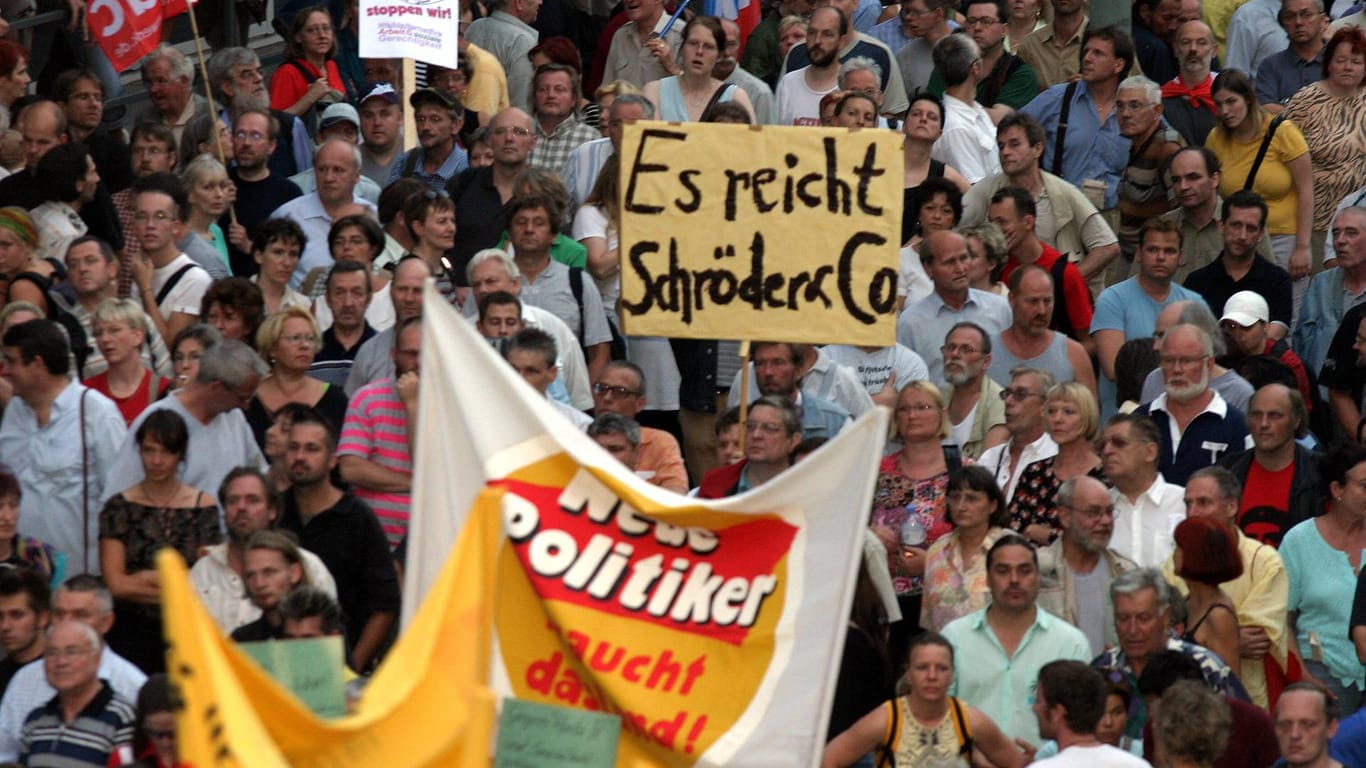 Menschen in Berlin demonstrieren 2004 gegen die umstrittenen Arbeitsmarktreformen des damaligen Kanzlers Gerhard Schröder.