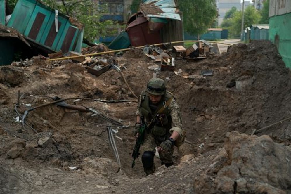 Ein Uniformierter inspiziert einen Krater nach einem Luftangriff der russischen Streitkräfte in der Region Luhansk.