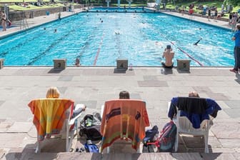 Badegäste sitzen in einem Schwimmbad in Liegestühlen (Symbolbild): Die Wassertemperatur wird in diesem Sommer in ganz München reduziert.