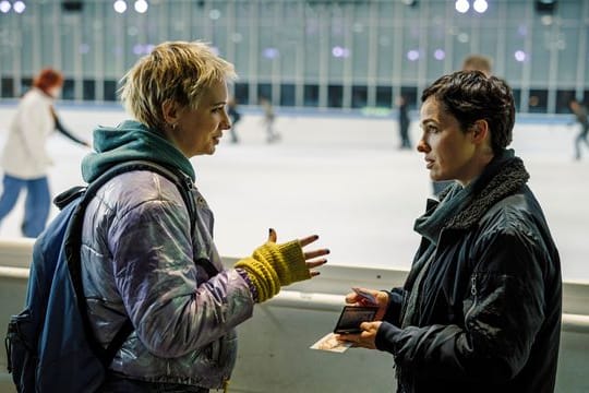 Bessie Eyckhoff (Verena Altenberger, r) befragt in der Eishalle Stefanie Reither (Zoë Valks) und zeigt ihr das Foto von Laura.