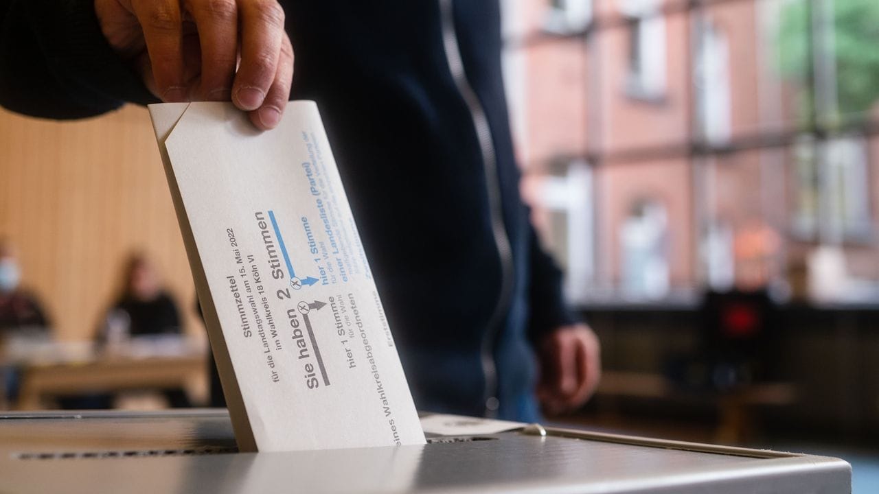 Ein Mann wirft in Köln seinen Stimmzettel in die Wahlurne.