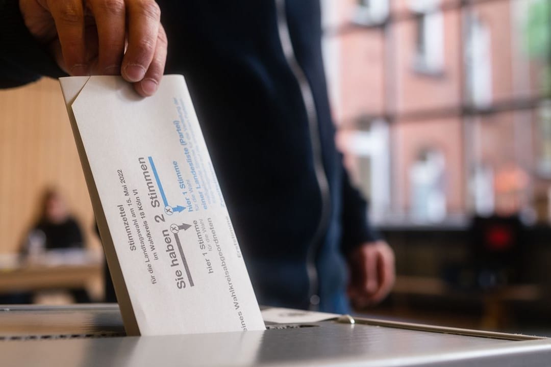 Ein Mann wirft in Köln seinen Stimmzettel in die Wahlurne.