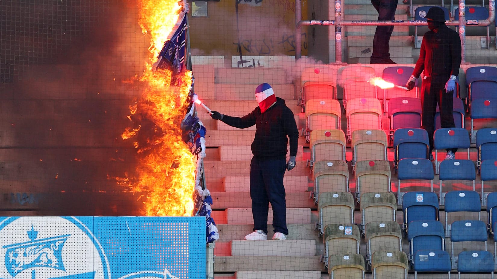 Die Kontrolle verloren: Rostocker "Fans" setzen HSV-Banner am Trennzaun zum Hamburger Fanblock in Brand.