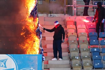 Die Kontrolle verloren: Rostocker "Fans" setzen HSV-Banner am Trennzaun zum Hamburger Fanblock in Brand.