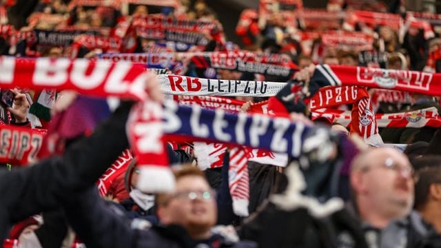 Fans von RB Leipzig halten ihre Fanschals in die Höhe.